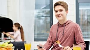 Young man at breakfast bar diagnosed with diabetes on phone watching the Patient Better Academy videos.