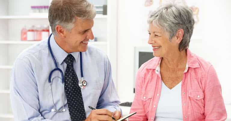 Physician and patient smiling in exam room, symbolizing strong health relationships.