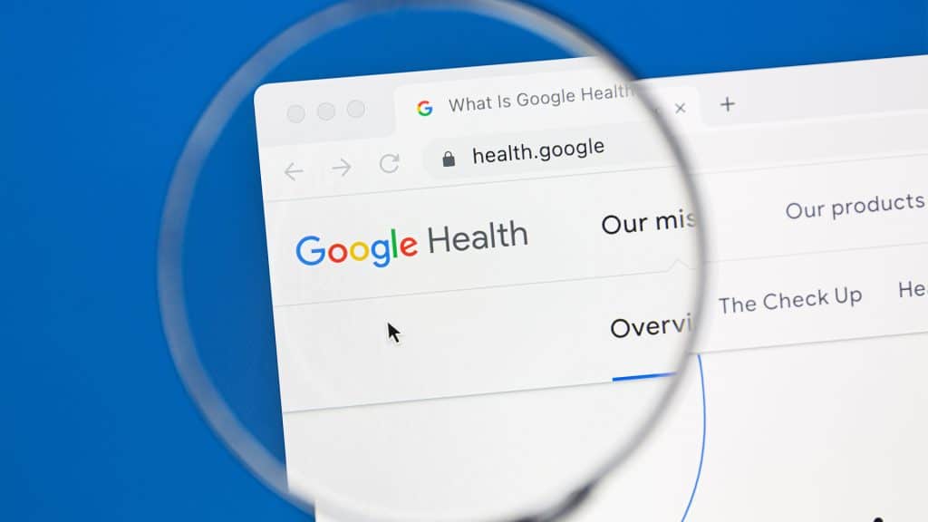 Google Health' in the search bar, magnified under a glass, symbolizing the search for virtual health resources.