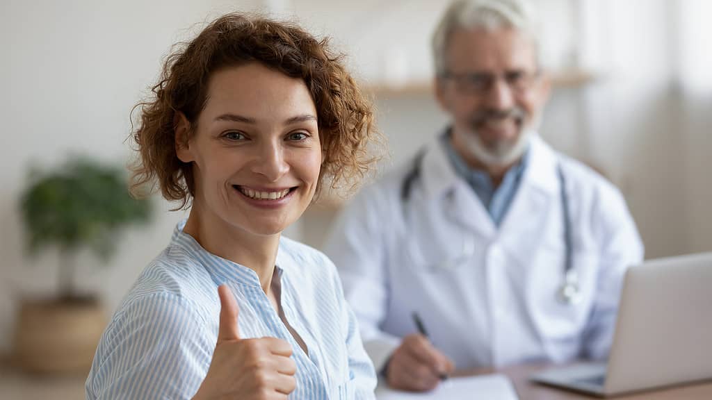 A smiling healthcare worker with a physician in the background, representing a 'health advocacy program.