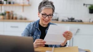 An older adult with glasses smiling while looking at documents, possibly reviewing information provided by advocacy services.