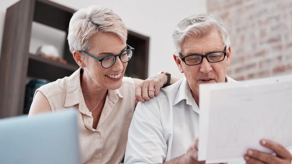 An elderly couple reviewing medical paperwork together, possibly as part of a healthcare advocacy program.