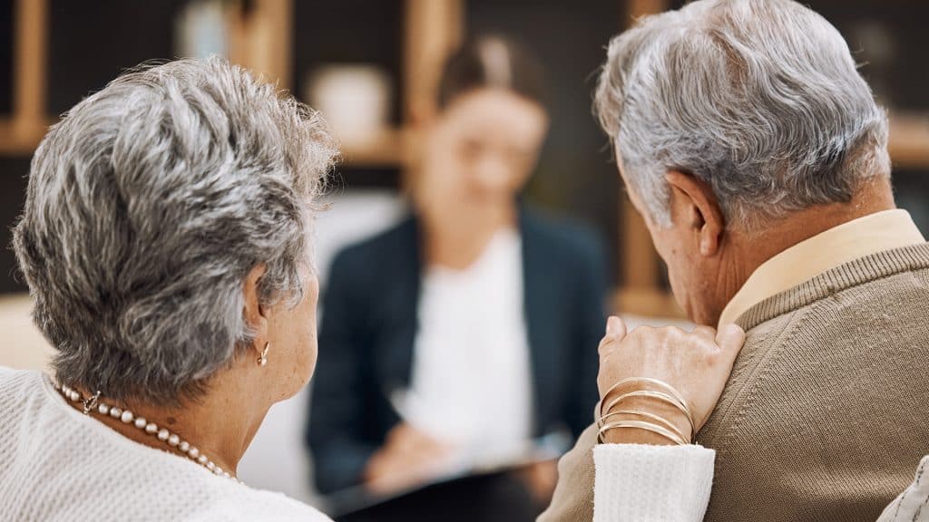 An elderly couple consulting with a healthcare professional, focusing on 'Coordinating Care Plans' for their health needs.