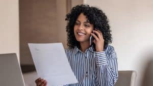 A woman reviewing a document while speaking on the phone, possibly discussing patient rights or healthcare information.