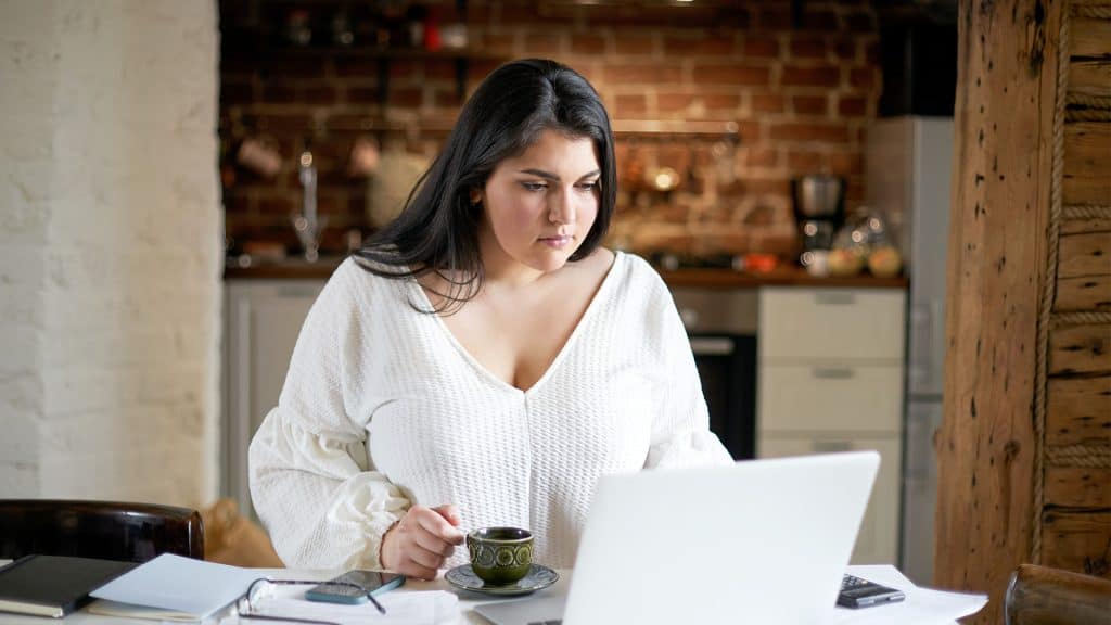 A woman intently reviewing medical paperwork at home, illustrating 'Patient Understanding' of healthcare information.