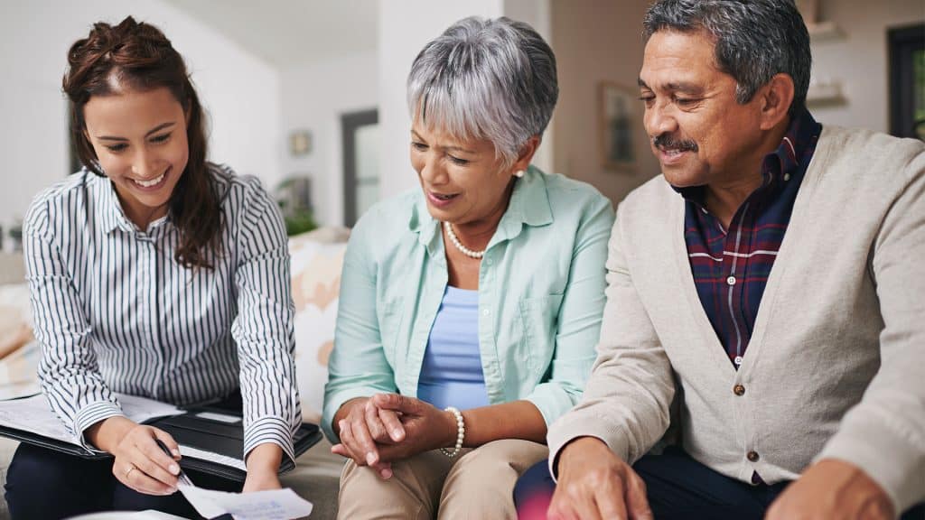 A healthcare professional with a senior couple, going over documents together, exemplifying 'patient-centered care.'