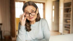 A woman adjusting her glasses and smiling, suggesting a proactive approach to Personal Health Management.'