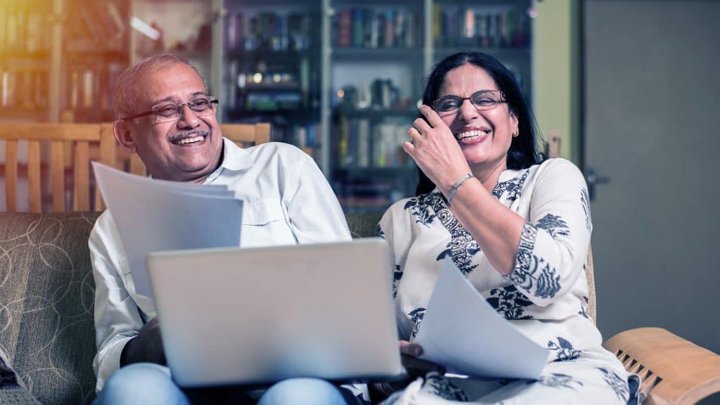 A joyful mature couple using a laptop together, likely researching or making decisions about their health, exemplifying to take charge of your health.