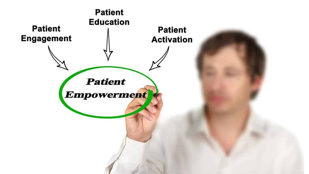 A man drawing a diagram on a clear board, highlighting the concept of patient empowerment through education, engagement, and motivation."