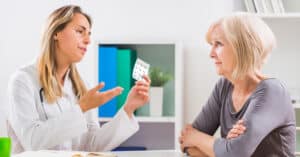 A healthcare professional explaining medication to a skeptical elderly woman, depicting a scenario with a difficult patient.