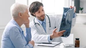 A doctor discussing an X-ray with an elderly patient, depicting 'Honest Communication' in a medical consultation.