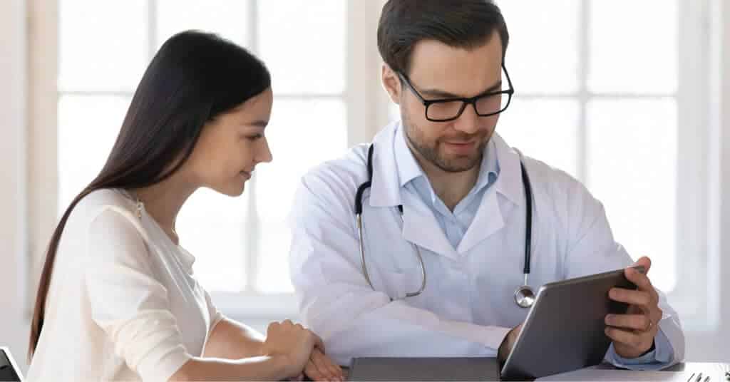 A patient and a doctor review information on a digital tablet, highlighting the importance of asking questions in a medical consultation.