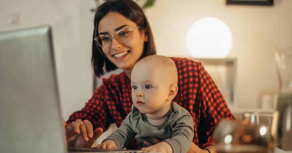 A smiling woman holding a baby, representing the concept of setting boundaries in family relationships.