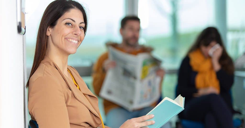 A confident woman in the foreground with individuals in the background, representing the concept of 'self-competence' in personal development or healthcare.