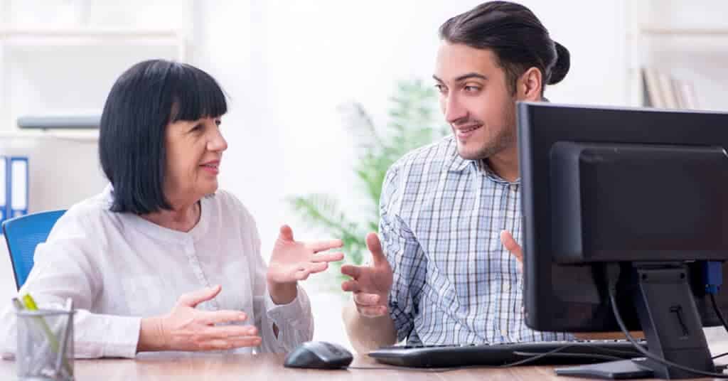 An engaged conversation between a patient advocate and an older woman at a desk, depicting the support provided by patient advocate programs.