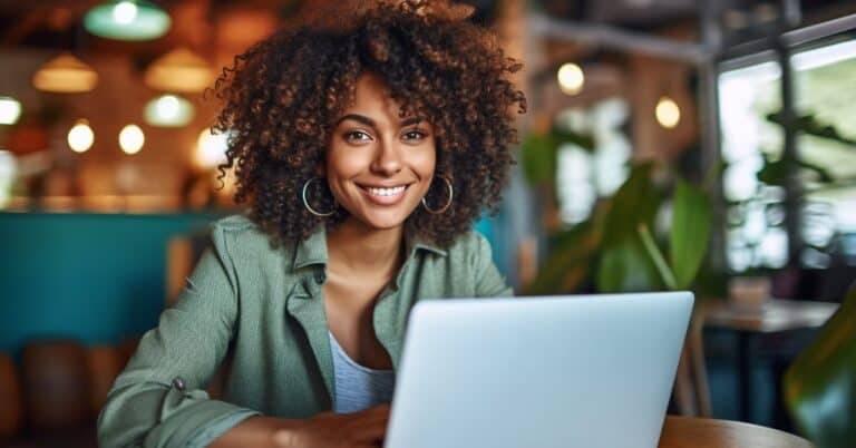 Woman smiling at the camera looking through Patient Better's site map on her lap top.