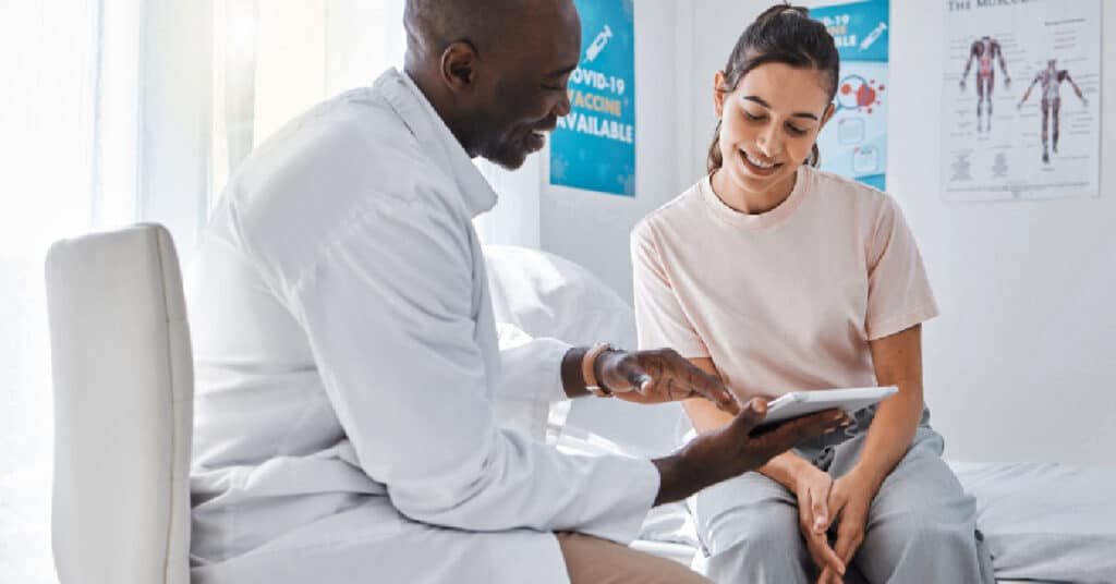 A physician and a patient review medical information on a tablet in a clinical setting, illustrating the principles of Evidence-Based Medicine (EBM). This approach involves integrating clinical expertise with the best available research evidence and patient values to make informed medical decisions.