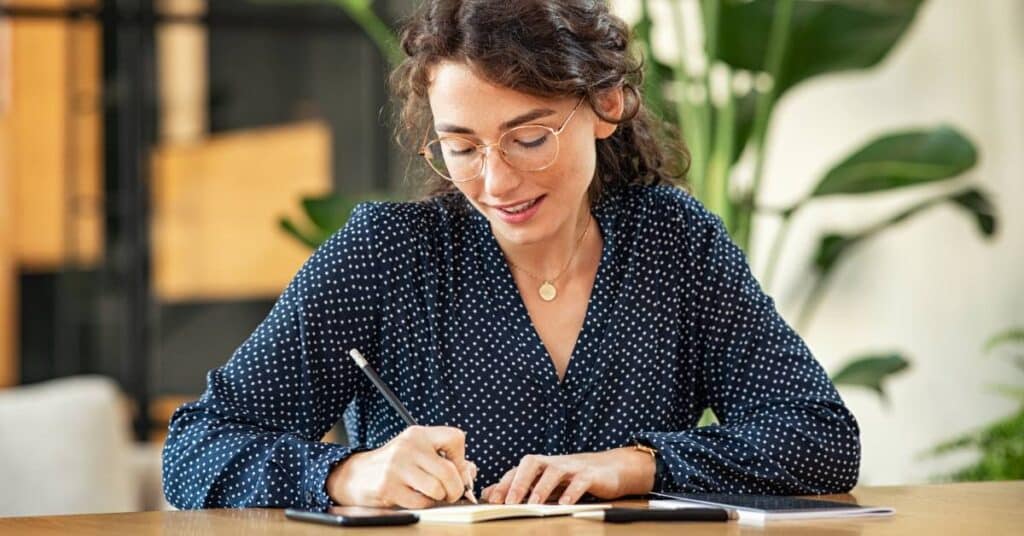 Woman writing notes while learning about health management programs designed to help patients manage conditions, prevent disease, and improve well-being.