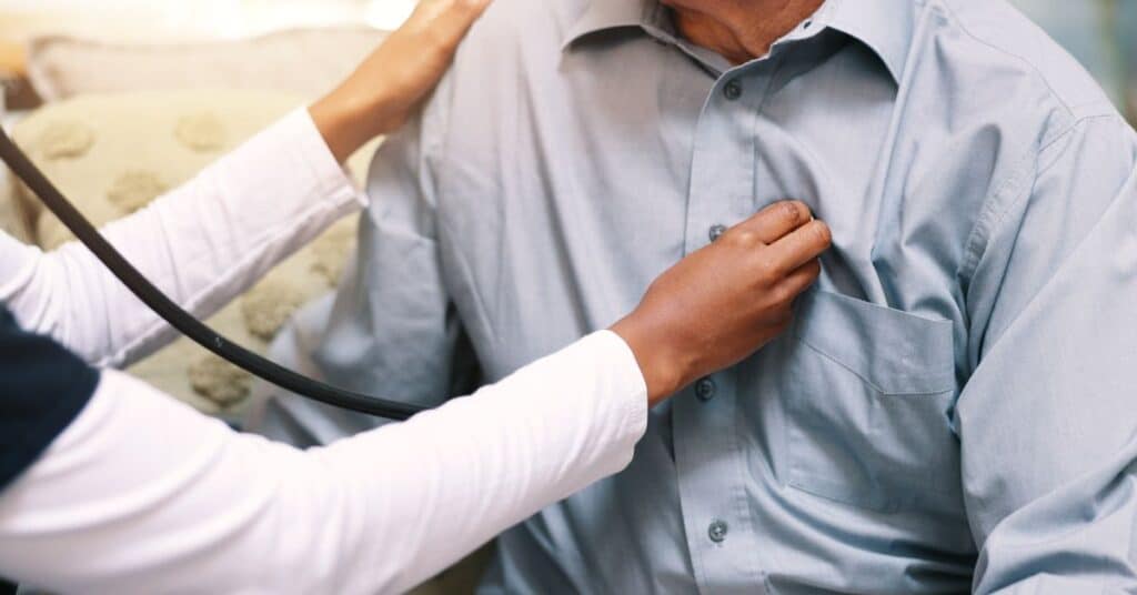 This image depicts a healthcare professional using a stethoscope to examine the chest of an elderly male patient, symbolizing the evaluation of a medical condition. The professional's hands are carefully placed to assess heart or lung function, a common practice in diagnosing and monitoring conditions like cardiovascular disease or respiratory disorders. The patient is seated in a calm environment, highlighting the compassionate and attentive care involved in managing medical conditions. This visual underscores the importance of routine check-ups and early detection in addressing health issues effectively.