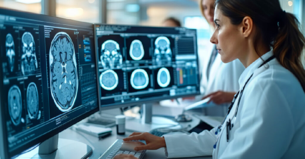 A medical professional analyzes brain scans on multiple monitors in a clinical setting, illustrating the use of telehealth technology. Telehealth enables healthcare professionals to securely communicate and share medical information across various schedules and time zones, enhancing collaboration and patient care.