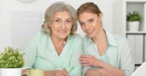 An elderly woman and her adult daughter smiling and working together on healthcare management, symbolizing the importance of understanding and managing CMS chronic conditions for better health outcomes.