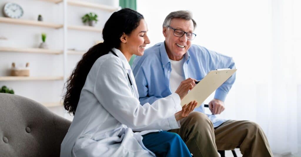 A healthcare provider in a white coat sits with an elderly male patient in a warm, well-lit room. They are both smiling as they review a clipboard together, symbolizing a collaborative and supportive approach to managing healthcare. The setting features a modern, organized background with shelves adorned with plants and minimal decor, adding a sense of calm and clarity. This scene captures the essence of healthcare navigation, emphasizing patient-provider communication, informed decision-making, and access to resources.