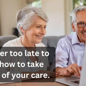 An older couple sits side by side at a dining table, smiling warmly as they look at a laptop screen together. The man, wearing glasses and a light purple shirt, points at the screen while the woman, in a white blouse, watches attentively. The mood is positive and engaged. A black text overlay on the image reads: “It’s never too late to learn how to take control of your care.”