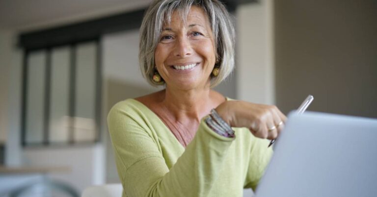 Confident older woman researching HEDIS vs CAHPS on her laptop, learning about healthcare quality measures and patient experience differences.