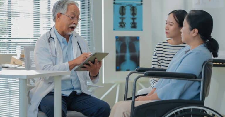 Doctor discussing care with a patient in a wheelchair and her caregiver, illustrating how the patient x-factor shapes personalized healthcare experiences.