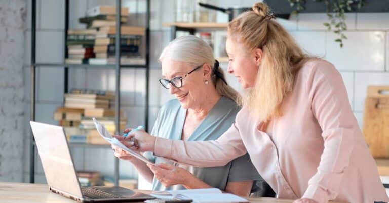 Social determinants of health influence how people live and access care, shown by two women reviewing health and financial documents together in a supportive home setting.