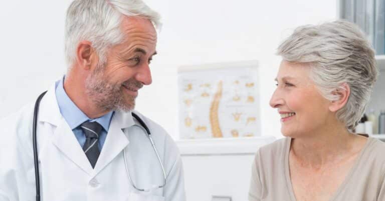 Doctor smiling at a patient during consultation, representing yes culture in healthcare where patients may agree without fully understanding decisions.