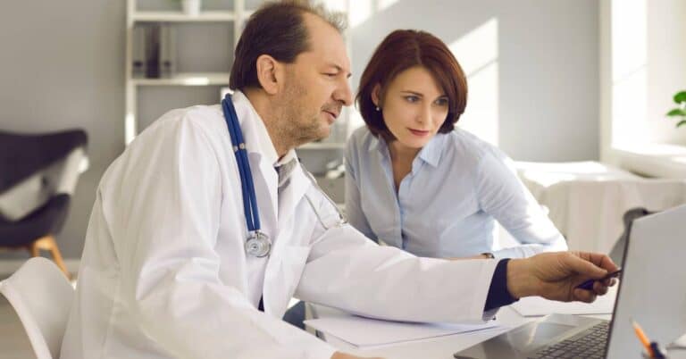 Doctor and patient reviewing medical information on a laptop illustrating how AI in healthcare supports decision-making and improves patient engagement.