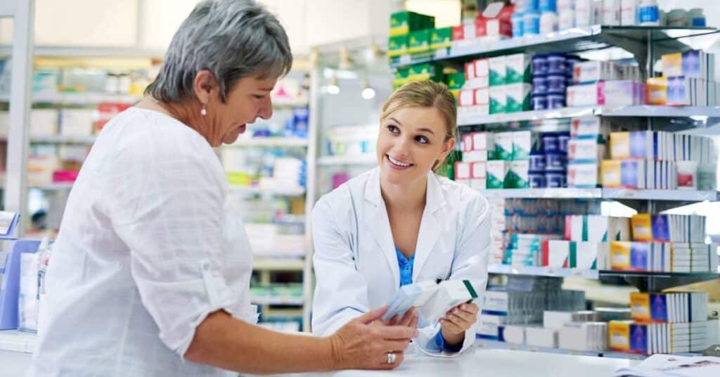 Pharmacist assisting a patient during the blood pressure drug recall 2025, explaining medication safety and recall instructions at a pharmacy counter.