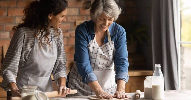 Eldest Daughter Syndrome illustrated by an adult daughter and her elderly mother smiling while baking together, symbolizing caregiving, family connection, and shared responsibilities
