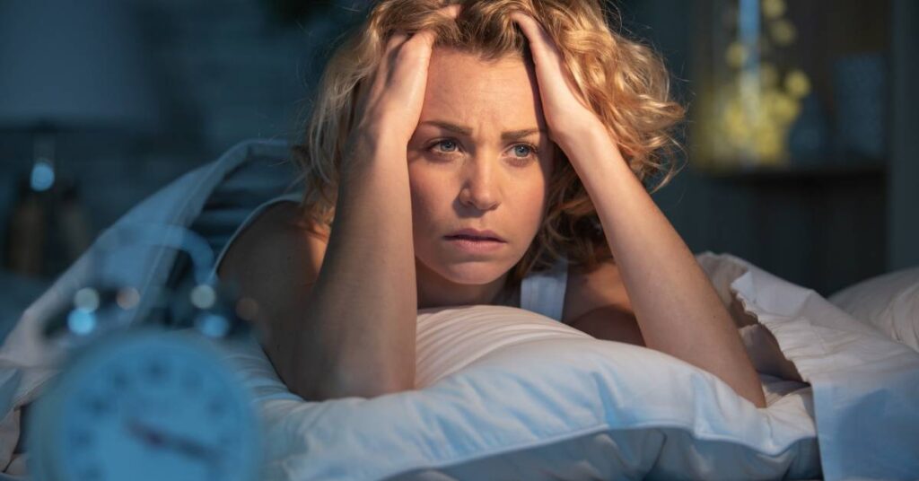 Woman lying awake in bed, thinking about what she forgot to say during her doctor visit — realizing she was not prepared for your appointment.