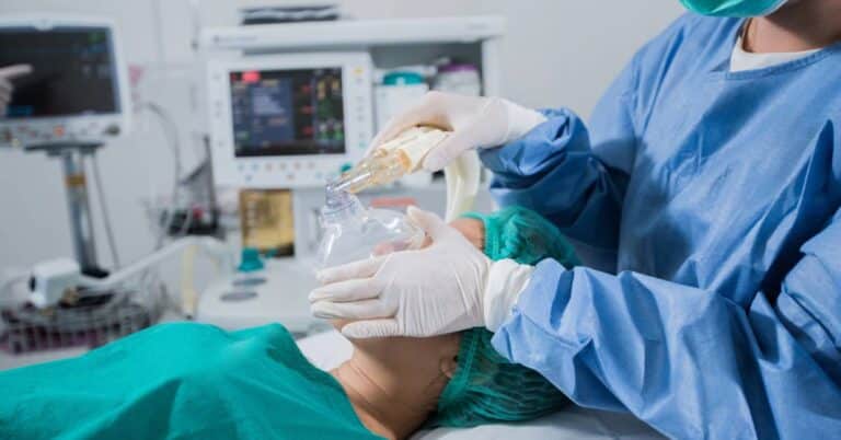 A medical professional administering general anesthesia to a patient in an operating room, illustrating how anesthesia is used to ensure comfort and safety during surgery.