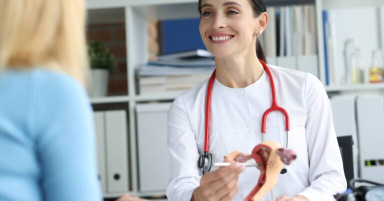 An OB-GYN doctor explains female reproductive health using a pelvic model during an obstetrics and gynecology consultation, guiding a patient through prenatal and wellness care.