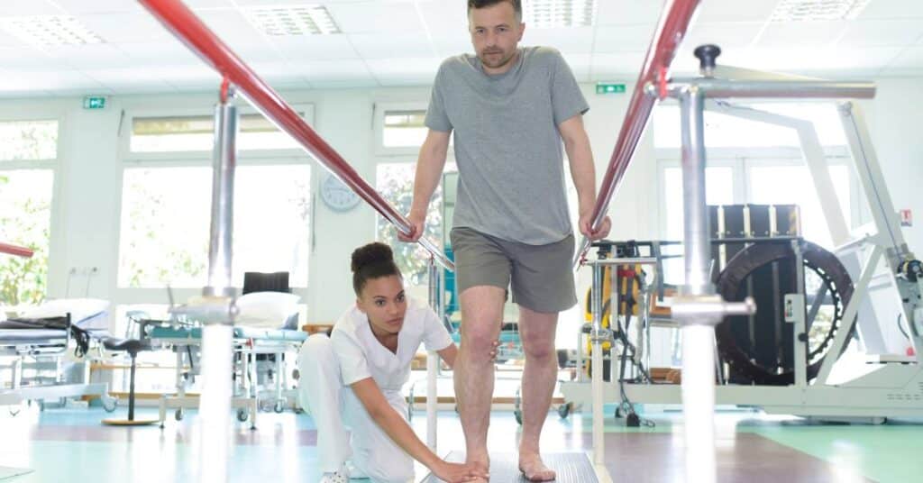 An occupational therapist helping a patient walk between parallel bars during rehabilitation therapy, demonstrating mobility recovery, adaptive training, and independence through occupational therapy.