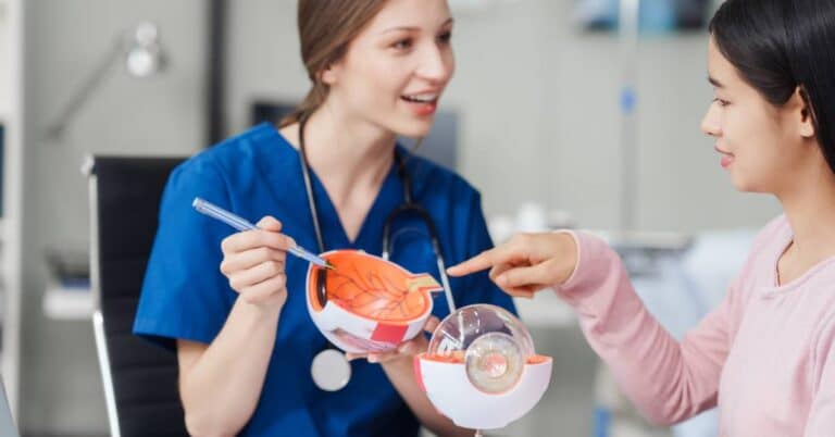 A healthcare professional explains eye anatomy using a model during an ophthalmology consultation, helping a patient understand vision care and eye health.