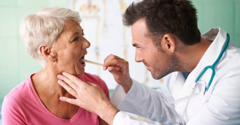 A doctor examining a patient’s throat with a tongue depressor, illustrating how otolaryngology focuses on ear, nose, and throat health and diagnosis.