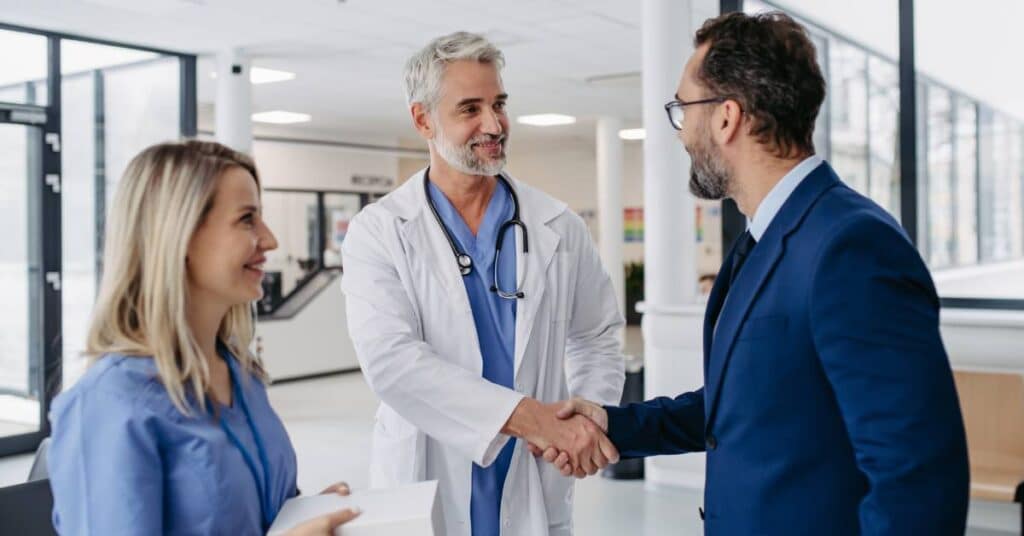 Doctor shaking hands with a professional in a hospital setting, symbolizing healthcare careers at Patient Better focused on collaboration, innovation, and patient advocacy.