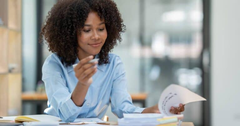 A woman reviewing paperwork at her desk, looking over documents related to medical coding for her recent healthcare services.