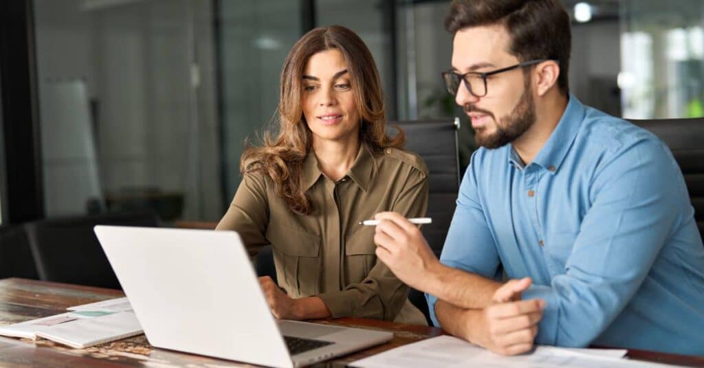 Two people reviewing documents on a laptop while discussing a prior authorization appeal process.