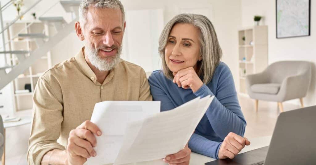 Older couple reviewing medical billing statements together at home, learning how to understand healthcare costs and insurance payments.