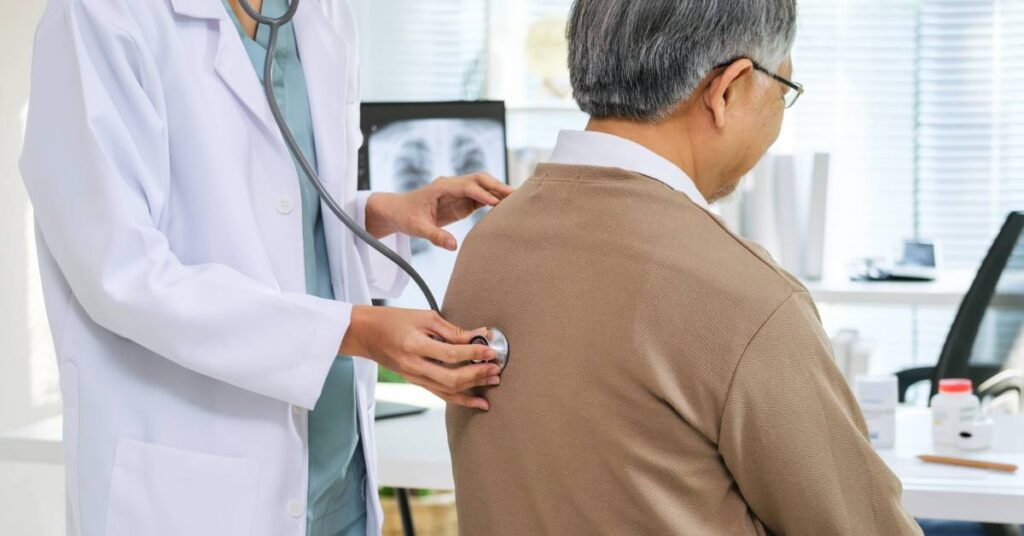 A doctor uses a stethoscope to listen to an older patient’s back during a check-up in a medical office, representing a healthcare service that would be documented using the Current Procedural Terminology (CPT) code system for accurate billing and insurance claims.