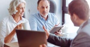 A mature couple sits with a financial or insurance advisor, reviewing healthcare costs together while discussing copay vs coinsurance.