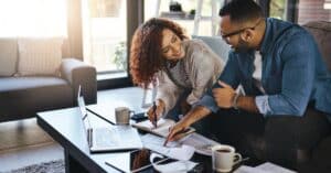 A couple reviewing paperwork and using a laptop to outsmart unexpected medical bills by checking costs upfront, tracking their medical information, and resolving billing questions together.