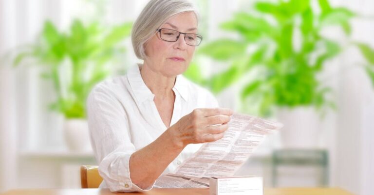 An older woman reviewing treatment instructions from a medication package, trying to understand how to follow her prescribed care safely.