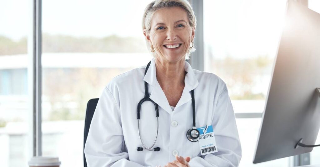Doctor in white coat smiling to support patient navigation handouts and visit-ready patient preparation