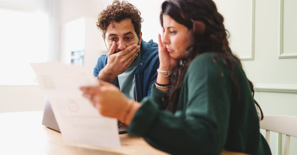 Couple reviewing a medical statement at home looking stressed over a billing error.